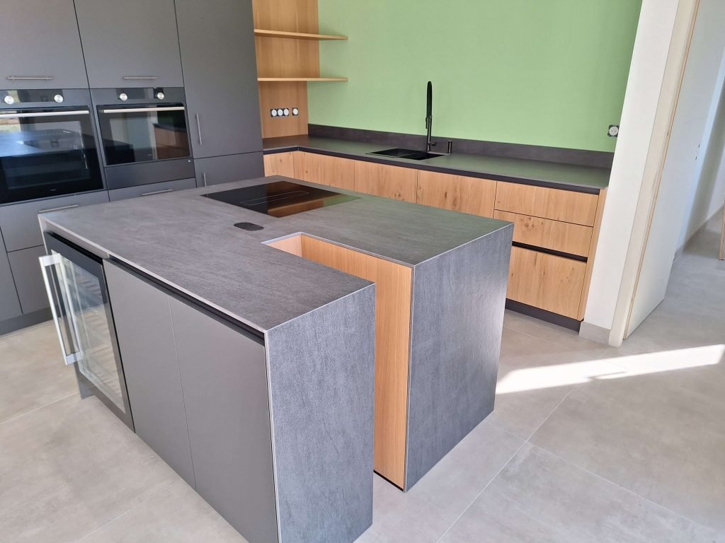 Ilot central d'une cuisine moderne et élégante aux tons gris et bois. Conception agencement par Idea Mobilier